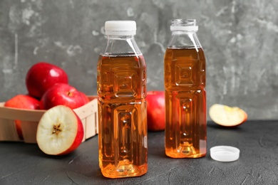 Bottles of apple juice on grey table