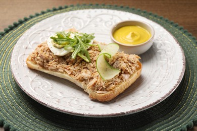 Photo of Delicious sandwich with tuna, boiled egg, vegetables and mustard sauce on green mat