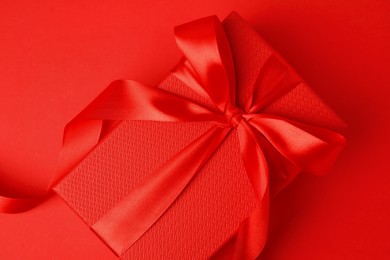 Beautiful gift box with bow on red background, top view