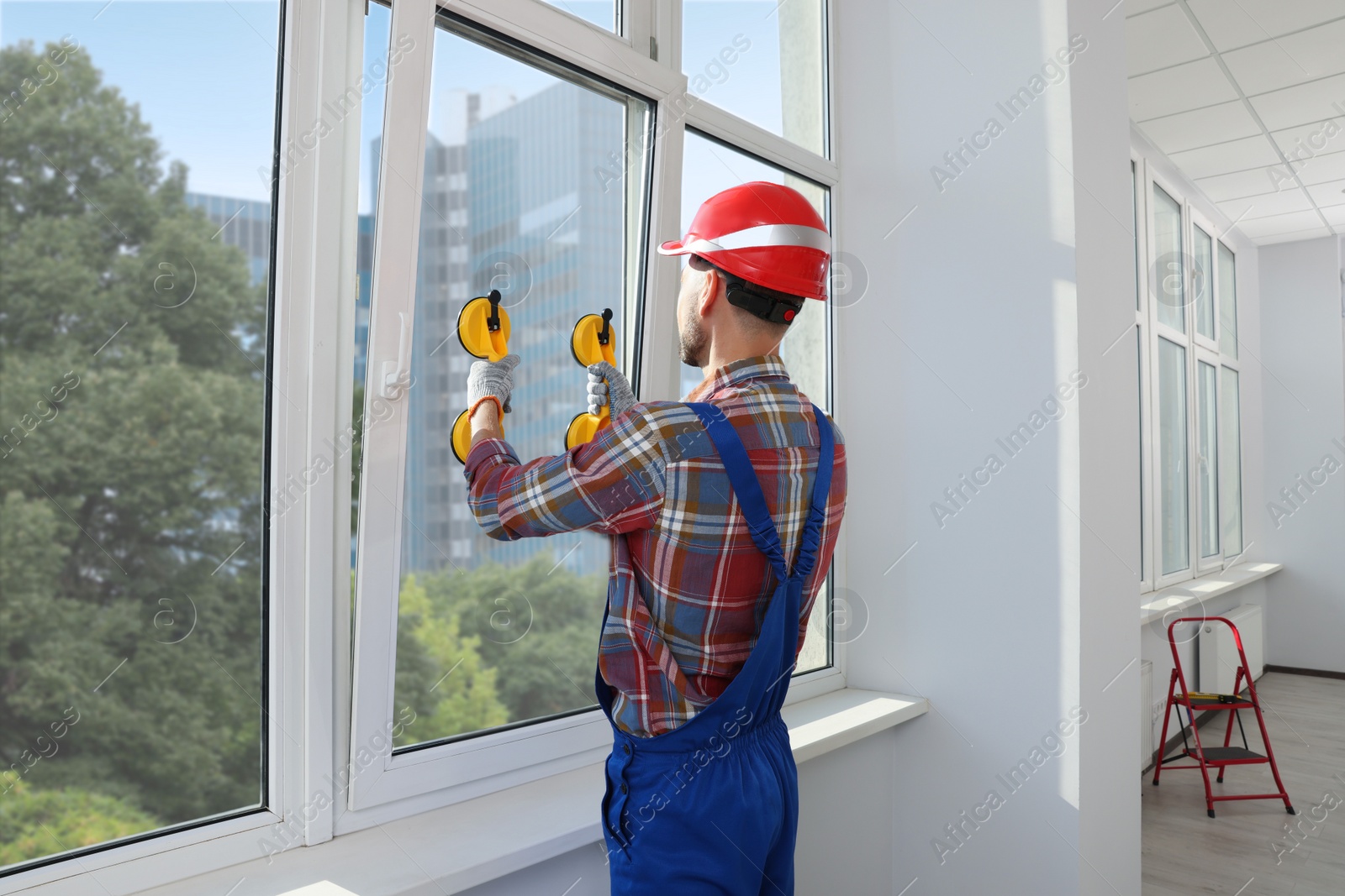 Photo of Worker using suction lifters during plastic window installation indoors