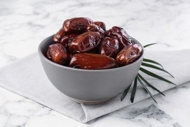 Photo of Sweet dried dates in bowl on white marble table, closeup