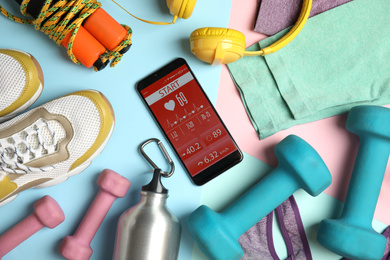Flat lay composition with fitness equipment and smartphone on light blue background