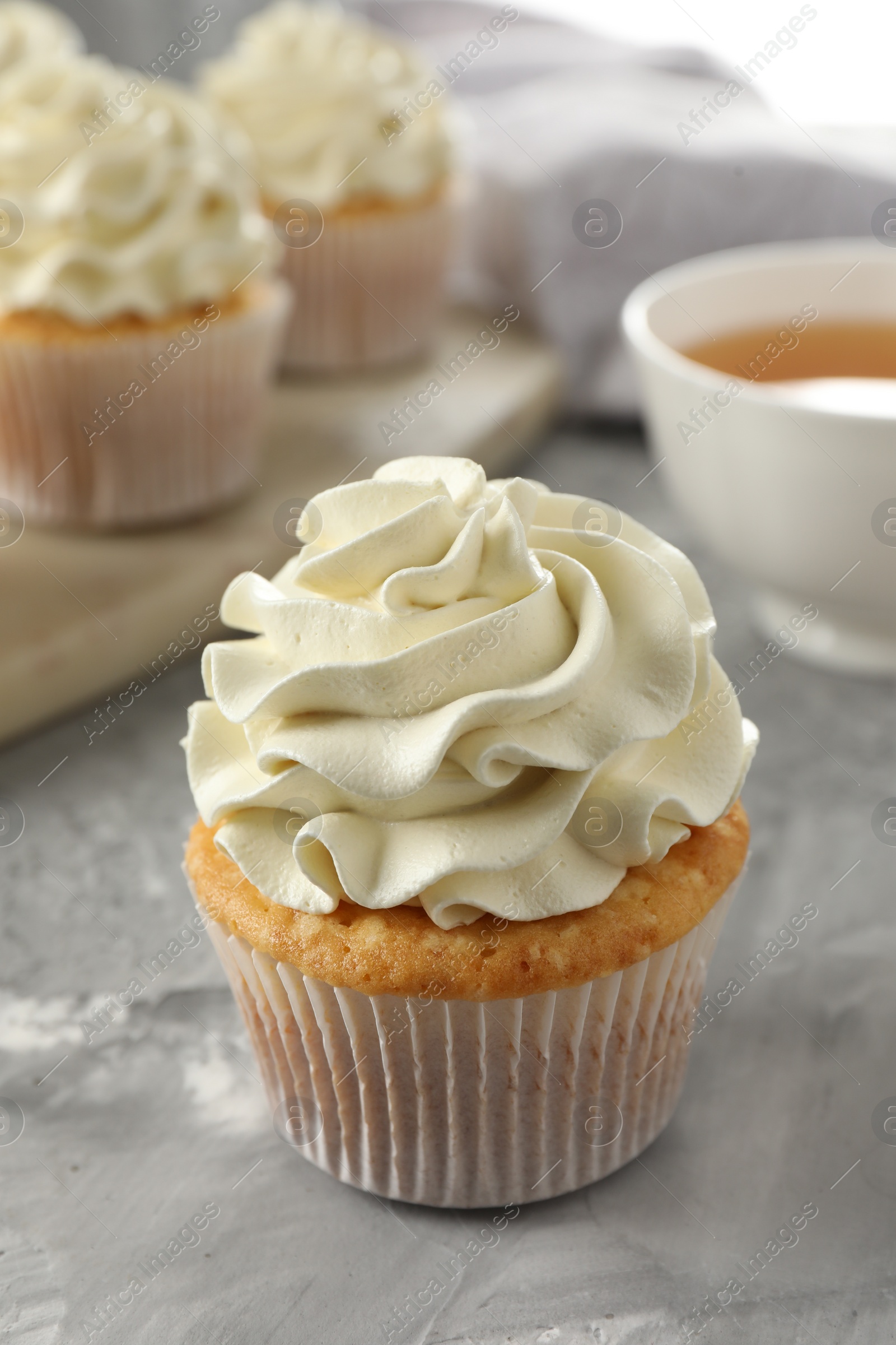 Photo of Tasty cupcake with vanilla cream on grey table, closeup