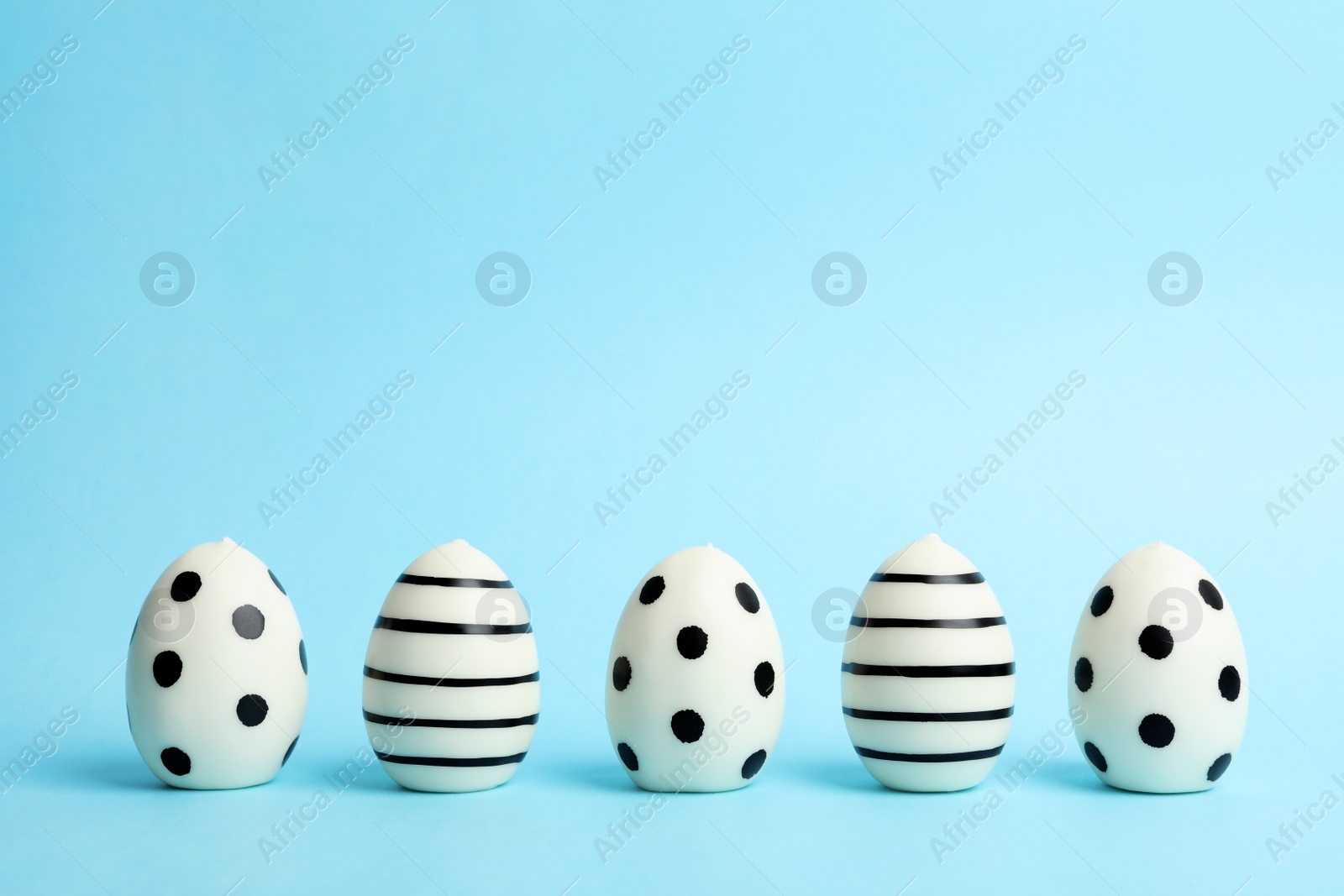 Photo of Line of traditional Easter eggs decorated with black paint on color background