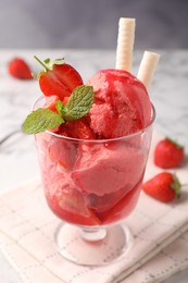 Photo of Tasty strawberry ice cream with fresh berries and wafer rolls in glass dessert bowl on table, closeup