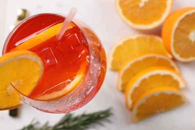 Glass of tasty Aperol spritz cocktail with orange slices on white table, top view