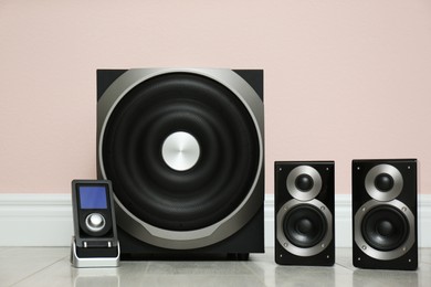 Photo of Modern powerful audio speaker system on floor near pink wall