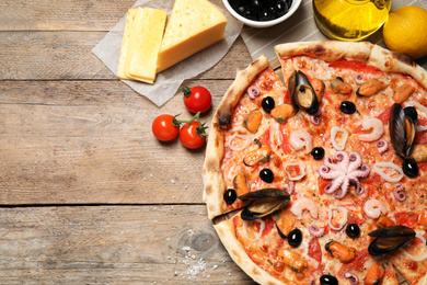 Photo of Tasty pizza with seafood and ingredients on wooden table, flat lay. Space for text