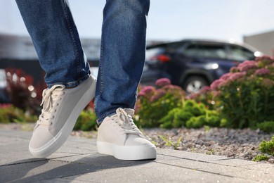 Man wearing pair of stylish sneakers outdoors, closeup