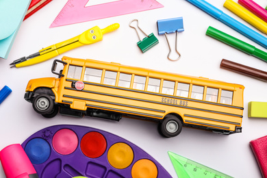 Photo of Flat lay composition with yellow school bus model on white background. Transport for students