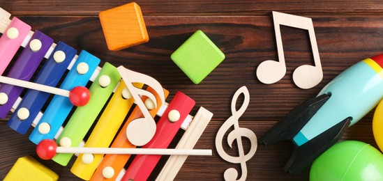 Photo of Baby song concept. Wooden notes, xylophone and toys on table, flat lay