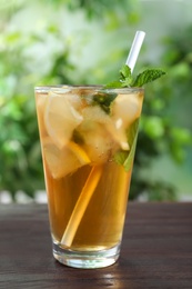 Photo of Delicious iced tea in glass on wooden table outdoors, closeup