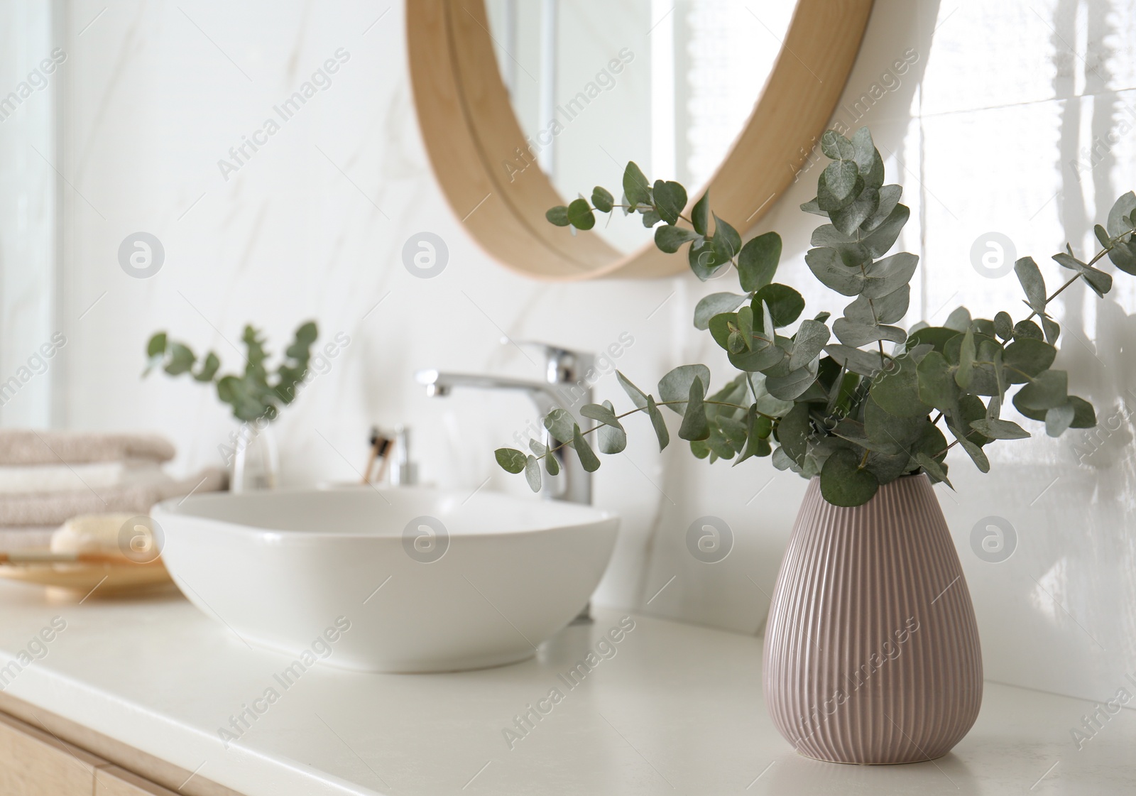 Photo of Fresh eucalyptus branches on countertop in bathroom