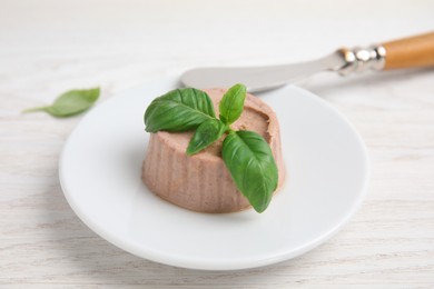 Plate with delicious meat pate and knife on white wooden table