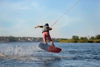 Teenage wakeboard doing trick on river, back view. Extreme water sport