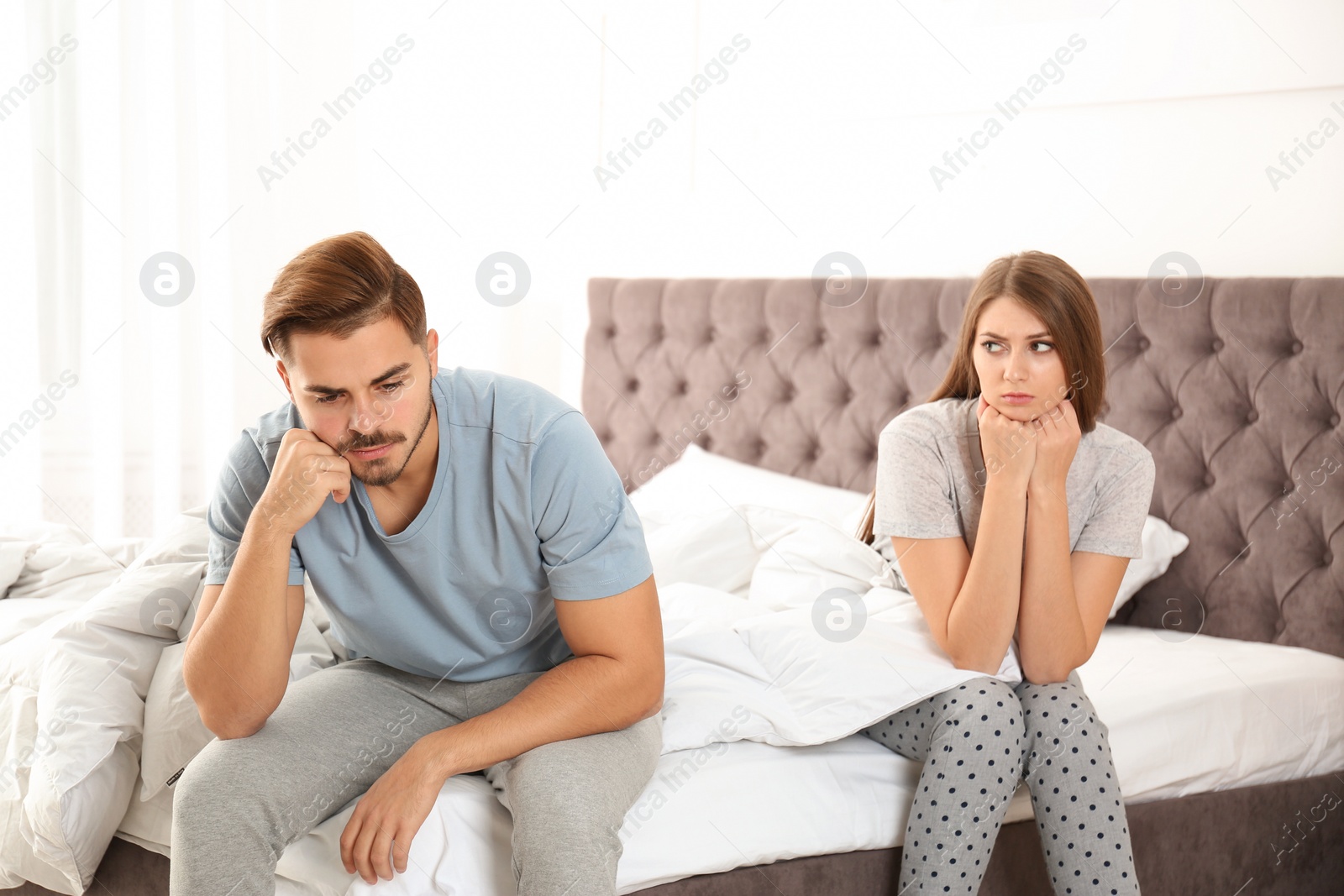 Photo of Upset young couple with relationship problems in bedroom