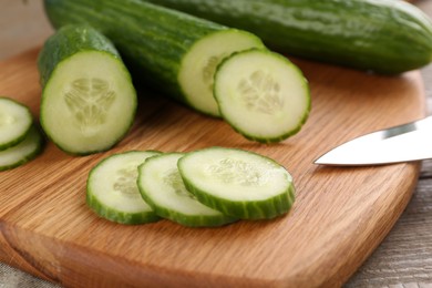 Photo of Cucumbers. knife and cutting board on table, closeup