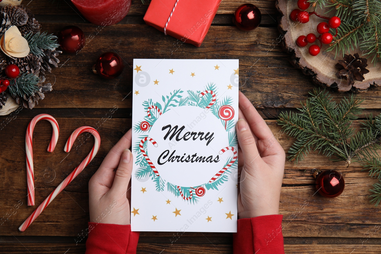 Photo of Woman holding Christmas card at wooden table, top view