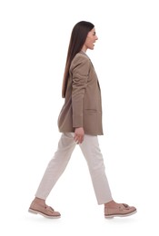 Beautiful young businesswoman walking on white background