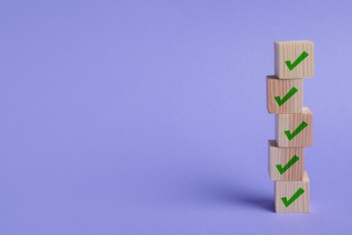 Image of Stacked wooden cubes with check marks on light violet background. Space for text