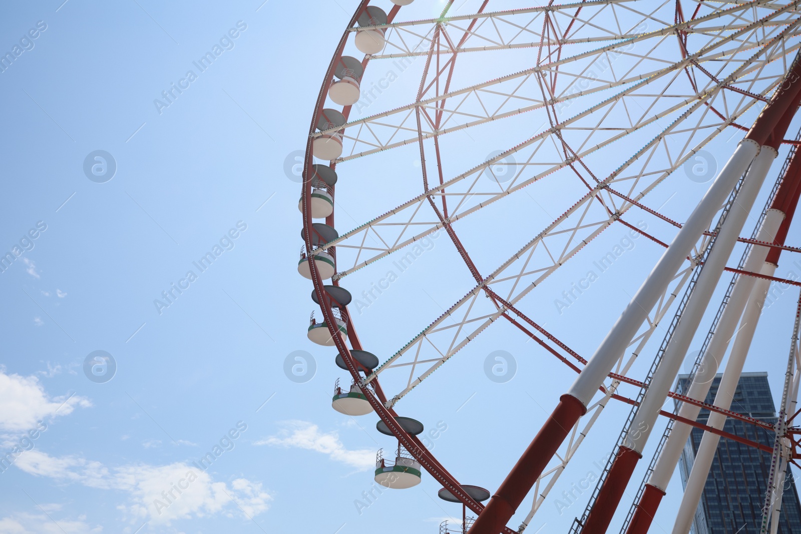 Photo of Beautiful large Ferris wheel against blue sky with clouds on sunny day
