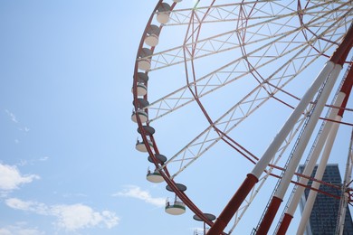Photo of Beautiful large Ferris wheel against blue sky with clouds on sunny day