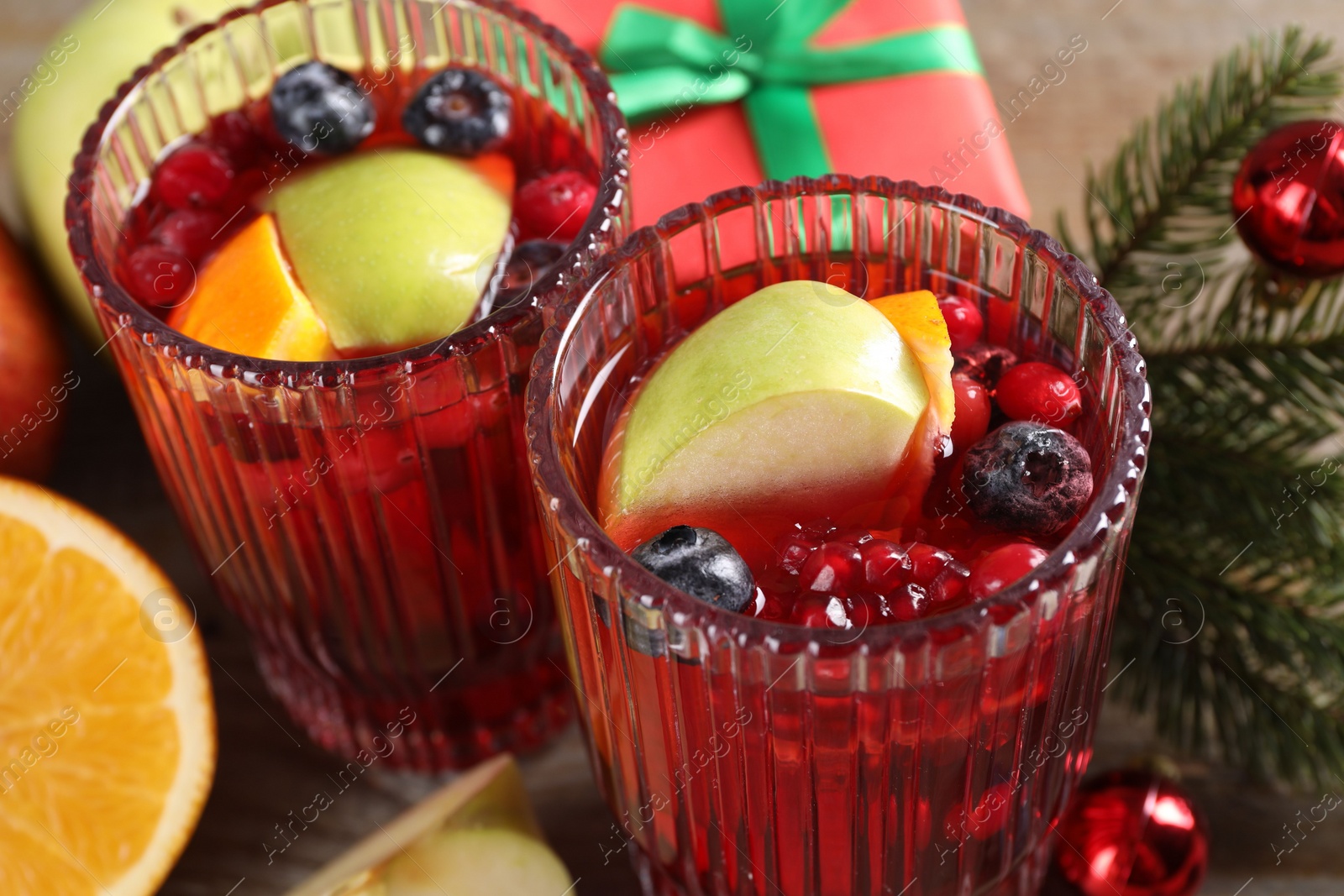 Photo of Aromatic Christmas Sangria drink in glasses on table, closeup