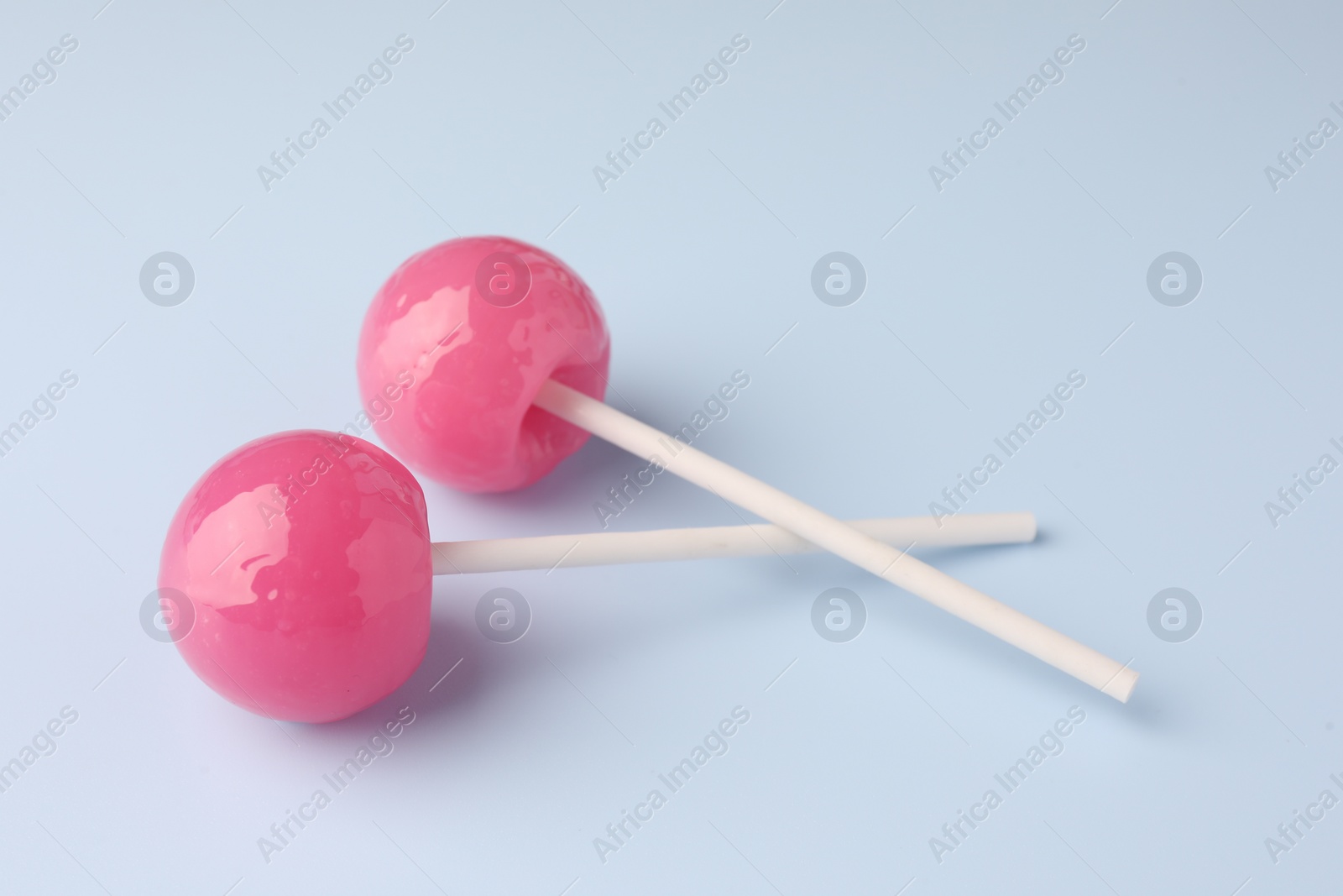 Photo of Tasty lollipops on light blue background, closeup