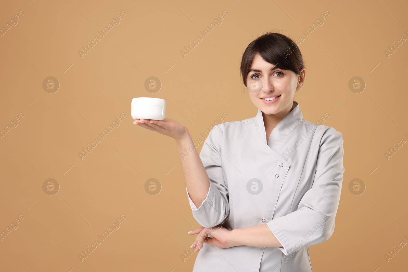 Photo of Cosmetologist with cosmetic product on beige background