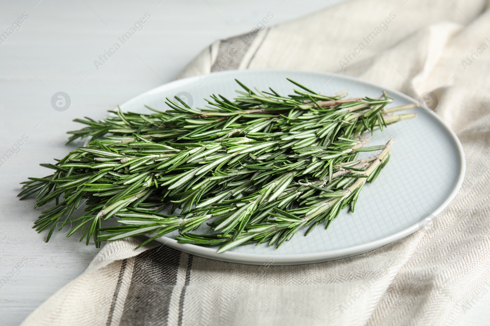 Photo of Plate with fresh rosemary twigs on wooden table