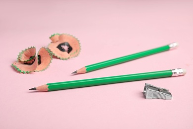 Photo of Pencils, sharpener and shavings on pink background