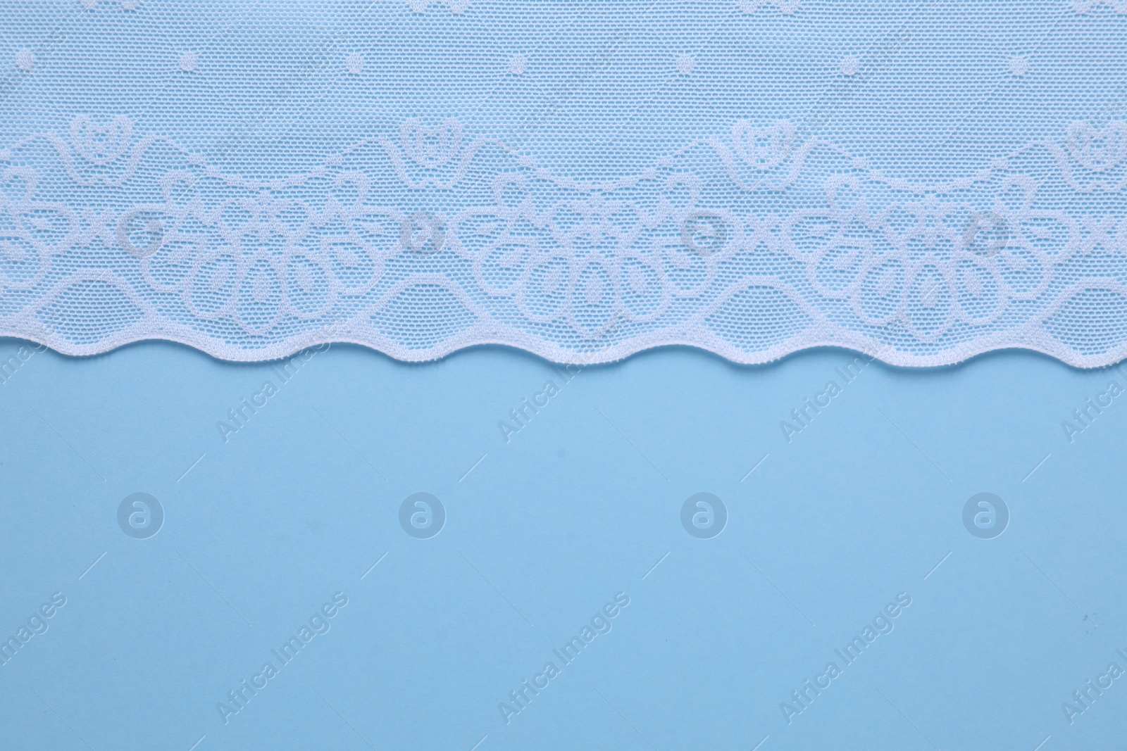 Photo of White lace on light blue background, top view. Space for text