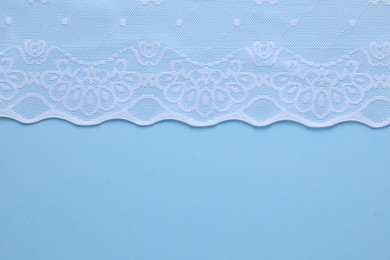 Photo of White lace on light blue background, top view. Space for text