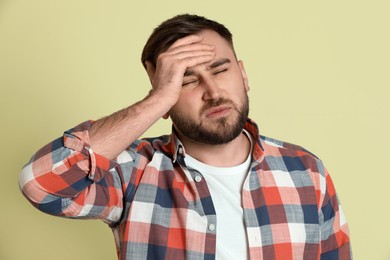 Photo of Man suffering from migraine on light green background