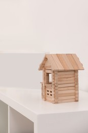 Photo of Wooden house on white shelf indoors, space for text. Educational toy for motor skills development
