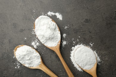 Photo of Baking powder in spoons on grey textured table, flat lay