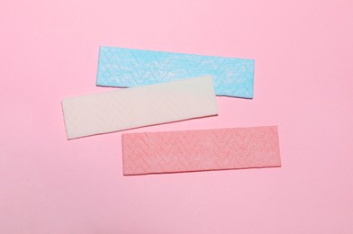 Photo of Sticks of tasty chewing gum on pink background, flat lay