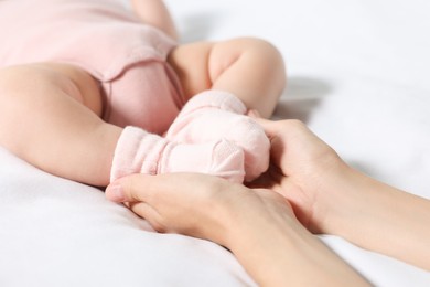 Photo of Mother holding legsher little baby on bed, closeup