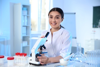 Photo of Female scientist with microscope in chemistry laboratory