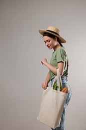 Photo of Woman with eco bag full of products on light background