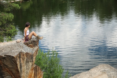 Photo of Young woman on rocky mountain near lake. Camping season