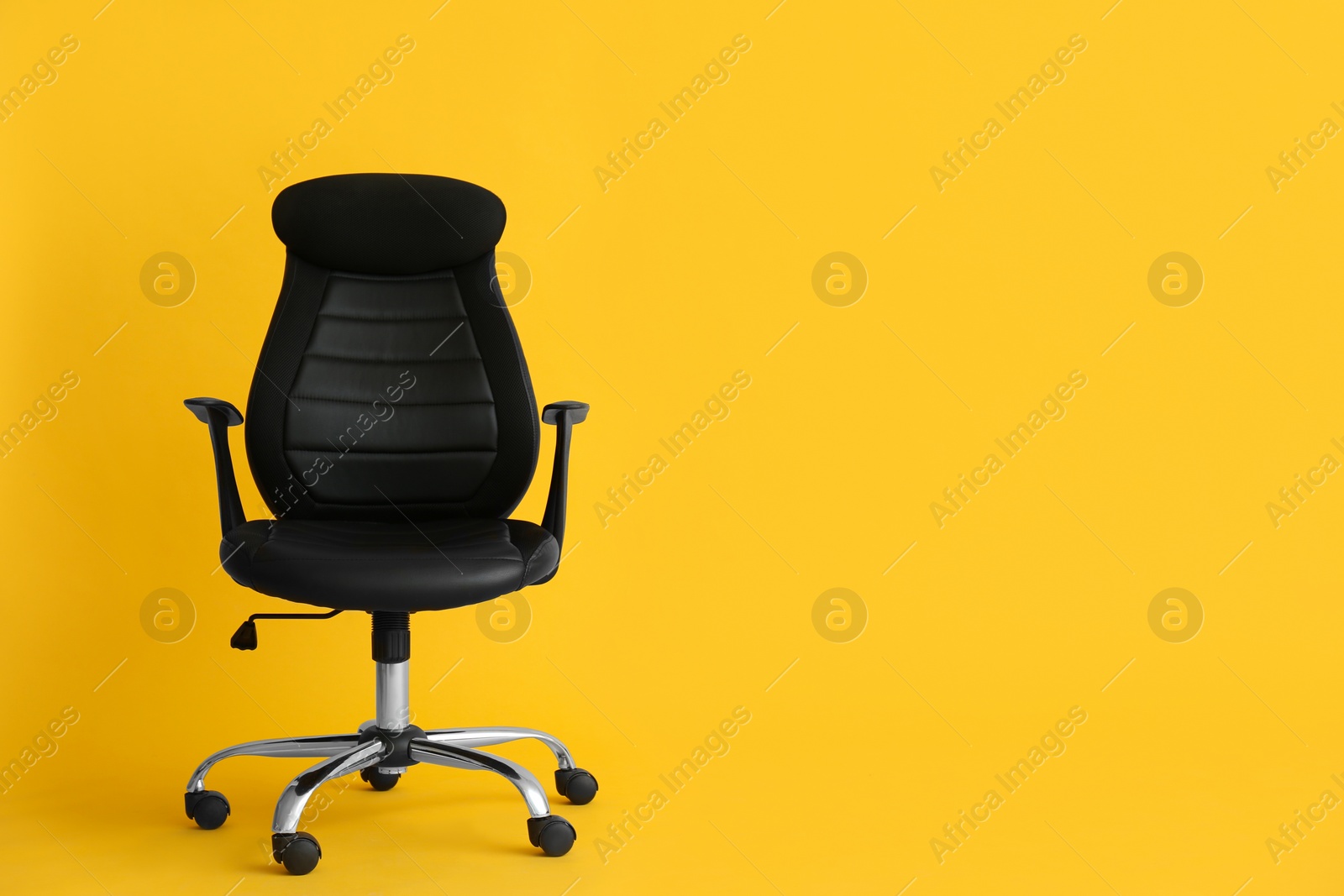 Photo of Modern office chair on yellow background. Space for text