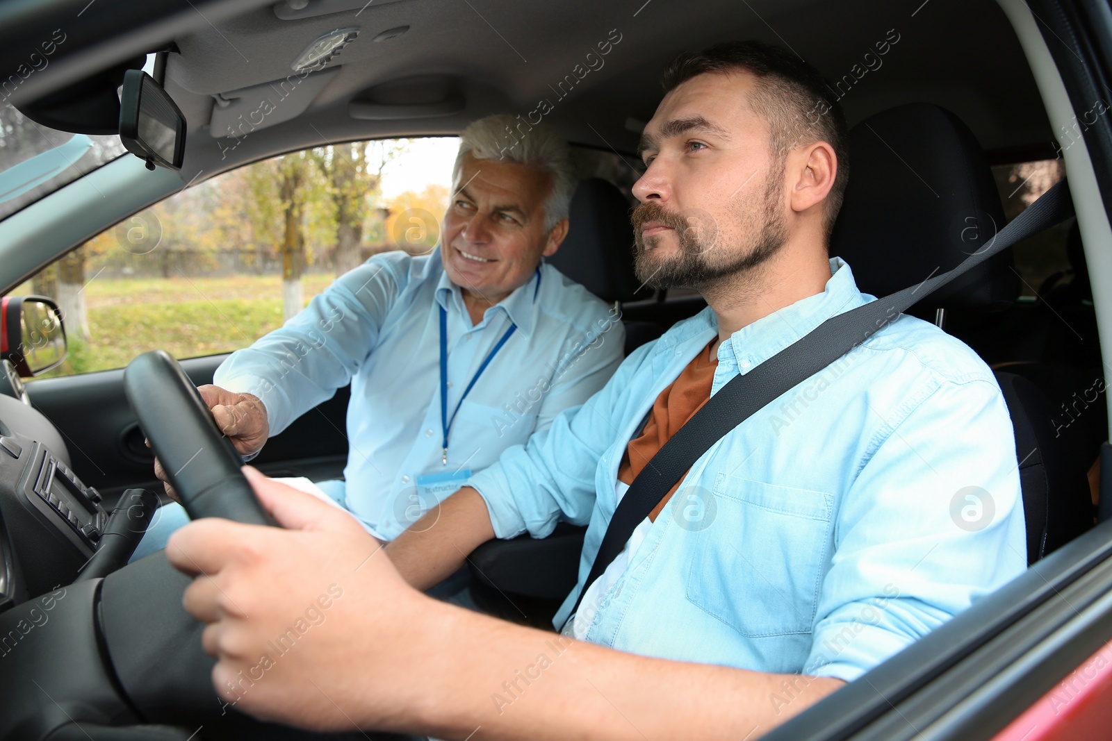 Photo of Man and instructor in car. Passing driving license exam