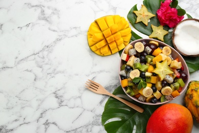 Photo of Flat lay composition with delicious exotic fruit salad on white marble table. Space for text