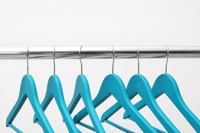 Photo of Clothes hangers on metal rail against light background