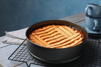 Photo of Delicious apricot pie in baking dish and cups on grey wooden table