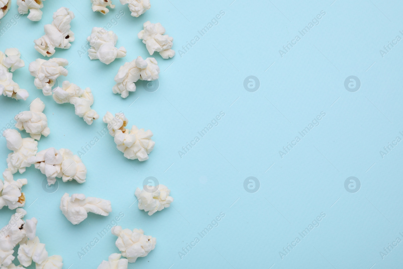Photo of Tasty popcorn on light blue background, flat lay. Space for text