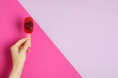 Photo of Woman holding delicious ice pop on color background, closeup view with space for text. Fruit popsicle