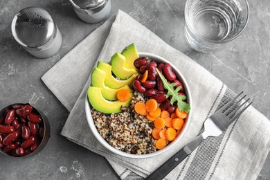 Photo of Healthy quinoa salad with vegetables in bowl served on table, top view