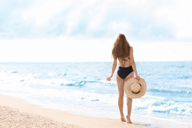 Photo of Attractive young woman in beautiful one-piece swimsuit on beach